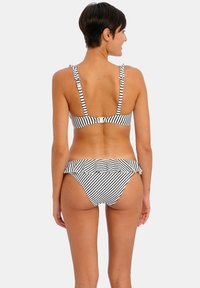 Bikini a righe bianche e nere con un cinturino volant, spalline regolabili e un design aderente, realizzato in un materiale liscio e elasticizzato.
