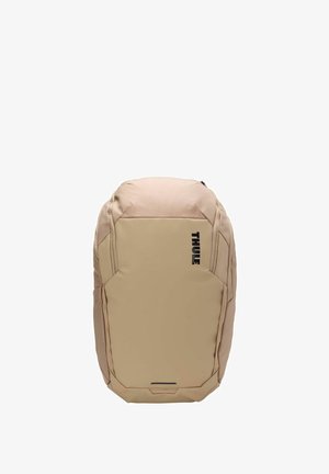 Sac à dos beige de forme arrondie, fabriqué en tissu résistant, arborant un logo noir, une fermeture éclair et un panneau avant texturé pour une meilleure prise en main.