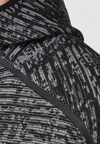 Close-up of black and gray textured fabric with a subtle striped pattern and black trim detail.