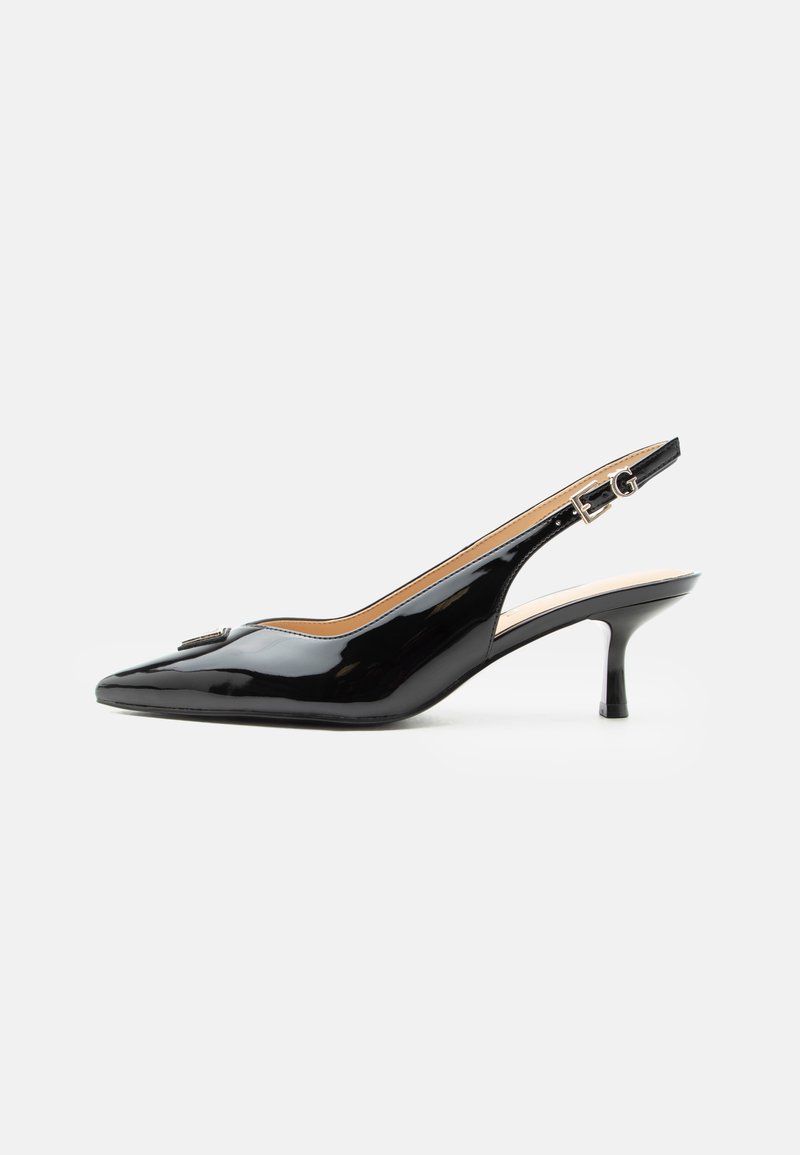 Escarpin slingback en cuir verni noir avec bout pointu, petit talon kitten et bride à boucle argentée sur fond blanc uni.