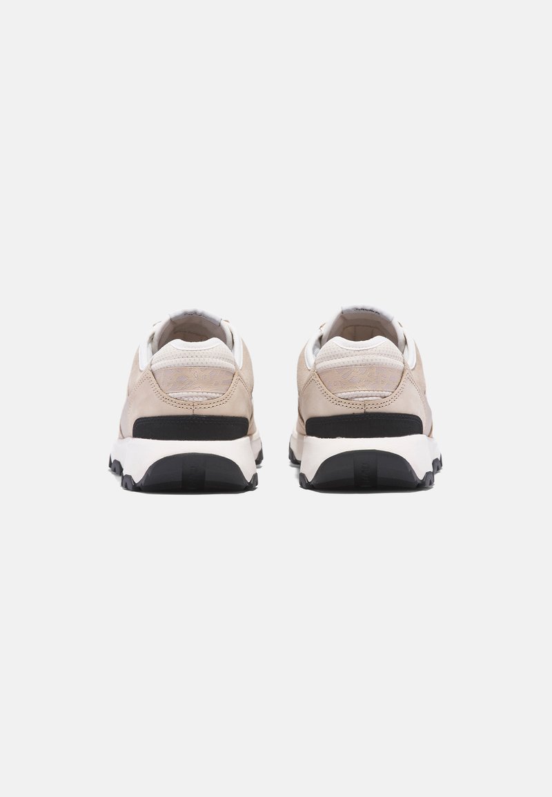 Beżowe sneakersy z fakturowaną cholewką, czarną podeszwą i białymi akcentami. Posiadają zaokrąglony kształt oraz wzmocniony obcas dla lepszego wsparcia.