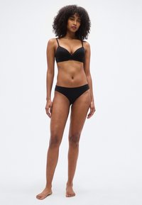 Sutien negru căptușit cu bretele reglabile, asortat cu chiloți tip bikini negri. Textură netedă, design minimalist. Fără modele sau accente.