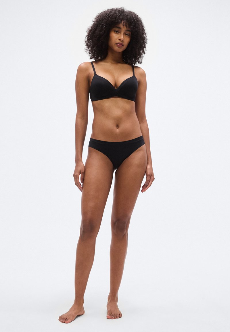 Sutien negru căptușit cu bretele reglabile, asortat cu chiloți tip bikini negri. Textură netedă, design minimalist. Fără modele sau accente.