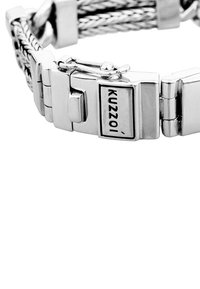 Silverfärgat metallarmband med flätad design, ett rektangulärt spänne märkt "Kuzzoi" och polerade sektioner med slät textur.