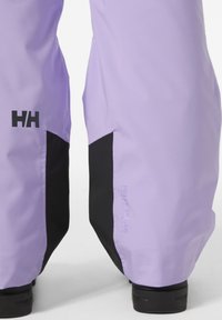 Fialové voděodolné kalhoty s černými akcenty, s logem "HH", značkou Helly Tech a hladkým, strukturovaným materiálem.