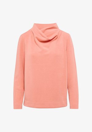 Bluzka w kolorze brzoskwiniowym z kapturem i długimi rękawami, wykonana z miękkiego materiału. Ma luźny krój i lekko zaokrąglony dół.