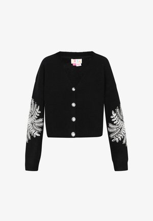 Mustat lyhytcroppinen neulejakku, jossa on syvä V-aukko, hopeanväriset napit ja monimutkainen valkoinen kukkakirjonta hihoissa. Pehmeä neulemateriaali.