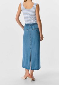 Gonna maxi in denim con vita elastica, color azzurro chiaro, tasche posteriori e spacco frontale. Abbinata a una canotta a righe.