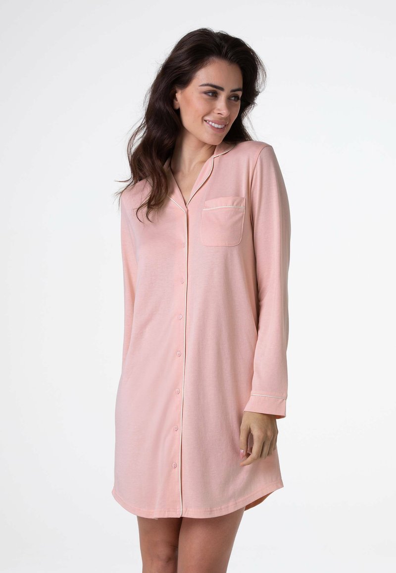 Camicia da notte rosa chiaro con bottoni, maniche lunghe, taschino sul petto, piping bianco lungo il colletto e orlo arrotondato. Tessuto morbido e leggero.