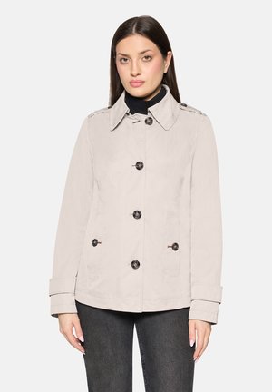 Hellbeiger Trenchcoat mit Knopfleiste, großem Kragen, Seitentaschen und aufgerollten Manschetten, aus einem glatten Stoff gefertigt.