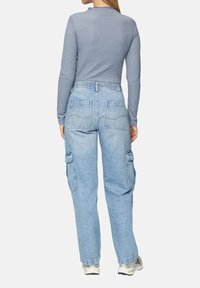 Helles blaues Langarmoberteil aus strukturiertem Stoff, kombiniert mit hellblauen Cargo-Hosen mit aufgesetzten Taschen und einer lockeren Passform.