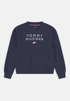 Felpa blu navy con scollo rotondo, maniche lunghe e polsini a costine. Presenta il logo "TOMMY HILFIGER" e un piccolo emblema a bandiera sul petto.