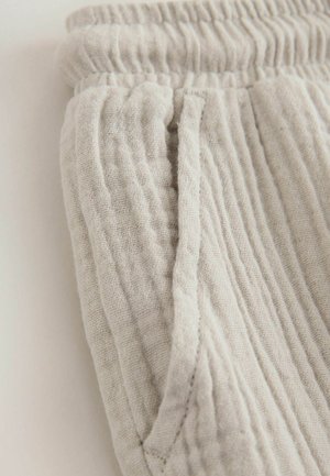 Ljusgrå, texturerade bomullsbyxor med elastisk midja och sidofickor, med ett mjukt, skrynkligt tyg.