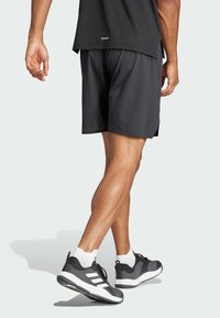 Svarta träningstights med mesh-textur, sidoflikar och avslappnad passform, kombinerat med svarta och vita sneakers och vita ankelsockor.
