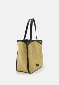 Sac fourre-tout en paille tissée de couleur jaune clair avec des accents et des poignées en cuir noir, présentant une forme rectangulaire spacieuse.