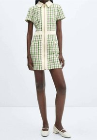 Vestito verde e bianco con motivo a fantasia, colletto, maniche corte e silhouette dritta. Presenta una cerniera frontale e una texture leggera.