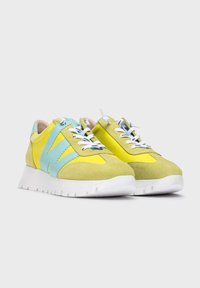 Zapatillas de ante amarillas y verdes con acentos en azul claro, cordones blancos y suela de goma blanca. Presentan paneles texturizados y lisos.