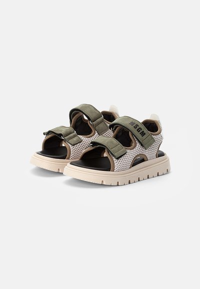 Sandálias de rede com base bege, tiras verdes-oliva e detalhes pretos. Apresentam fechos ajustáveis em Velcro e uma sola de borracha texturizada.