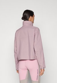 Short purple jacket with a high collar, featuring a straight cut and a smooth texture. The back has minimal stitching details and no visible fasteners.