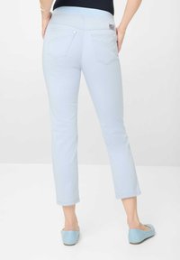Lichtblauwe cropped jeans met een zachte textuur, vijf zakken en subtiele stikdetails. G gedragen met blauwe instappers.