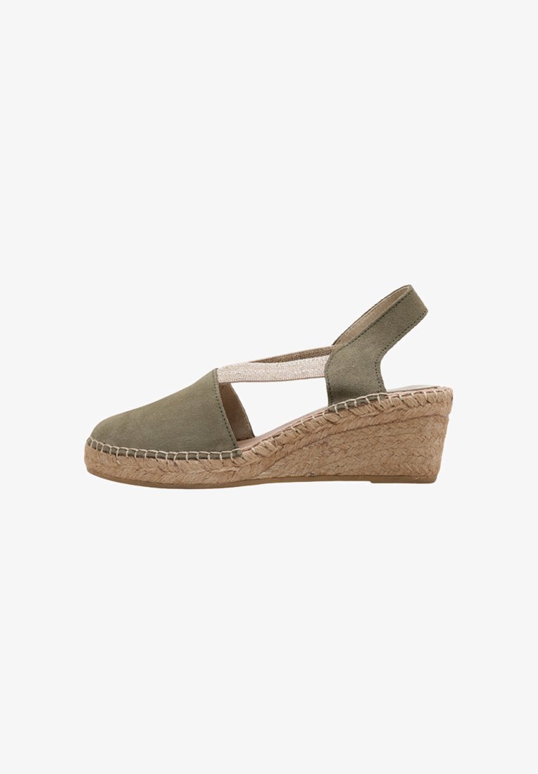 Espadrille en suede vert avec un bout fermé, une sangle élastique et une semelle en jute tissée. Présente une base texturée et un design simple.