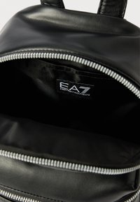 Czarny plecak z sztucznej skóry z zamkiem błyskawicznym, o gładkiej fakturze i z wewnętrzną metką z logo "EA7 Emporio Armani."