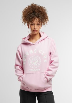 Rosa hettegenser med "LOVERS CLUB" grafikk, hvit rose-design, frontlomme og ribbestrikket kant. Stoffet ser mykt og teksturert ut.