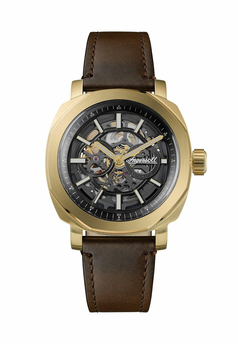 Orologio da polso con quadrante scheletrato color oro, ingranaggi visibili, indicatori neri e dorati, e cinturino in pelle marrone.