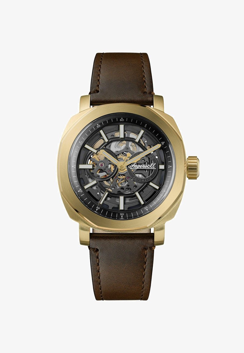 Orologio da polso con quadrante scheletrato color oro, ingranaggi visibili, indicatori neri e dorati, e cinturino in pelle marrone.