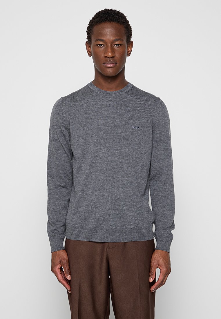 Maglione grigio a maglia con colletto tondo, maniche lunghe e polsini a coste. Presenta un piccolo logo sul petto e una texture liscia.