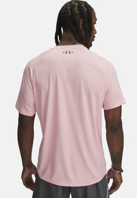 Růžové sportovní tričko s krátkým rukávem, texturovaná tkanina a logo na zadní straně. Má volný střih a zaoblený v ýstřih.