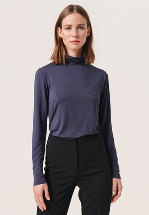 Marineblaues Langarm-Turtleneck-Top aus weichem, dehnbarem Material, kombiniert mit schwarzen, hochgeschnittenen Hosen. Glatte Textur und taillierte Passform.