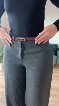 Gray tailored trousers with a smooth texture, flat front, and two side pockets, paired with a narrow burgundy belt featuring a silver buckle.