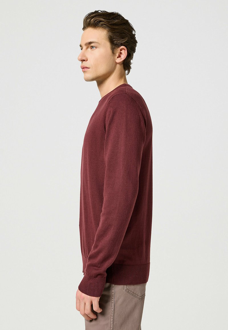 Pullover in borgogna con maniche lunghe, polsini e orlo a coste, realizzato in un tessuto morbido, con scollatura a girocollo e una silhouette adatta.