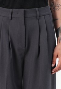Grijze geplooide broek met een hoge tailleband, riemlussen en voorkeurszakken, gemaakt van een gladde, gestructureerde stof.