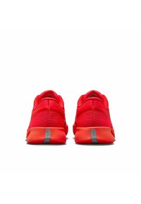 Ein Paar leuchtend rote Sportschuhe von hinten betrachtet, mit grauen reflektierenden Streifen an den Fersen vor einem weißen Hintergrund.