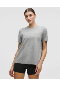 Grå kortärmad t-shirt i strukturerad tyg, med rund hals och avslappnad passform. Kompletteras med svarta shorts för kontrast.