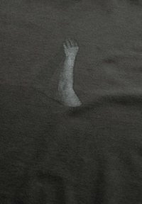 Zwart stoffen T-shirt met een vage grijze afbeelding van een opgestoken arm die vanuit de linksonder hoek komt, gladde textuur, casual ontwerp.