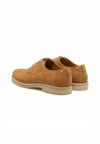 Chaussures en suède marron à lacets avec une texture lisse, bout rond et semelle en caoutchouc beige clair. Détails de couture subtils à l'arrière.