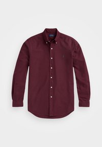 Långärmad skjorta i burgundy färg gjord av bomull. Har en knappfästad krage och en grön broderad logotyp på vänster bröst. Mjuk textur.