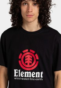 Camiseta de algodón negra con un gran gráfico rojo que presenta un símbolo de árbol y la palabra "Element" sobre un diseño circular.