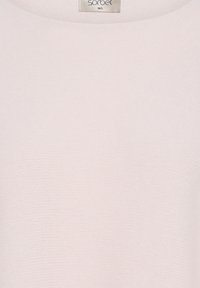 Tissu texturé rose clair avec un col rond et une étiquette de taille visible indiquant "sorbet M/L" en haut au centre.