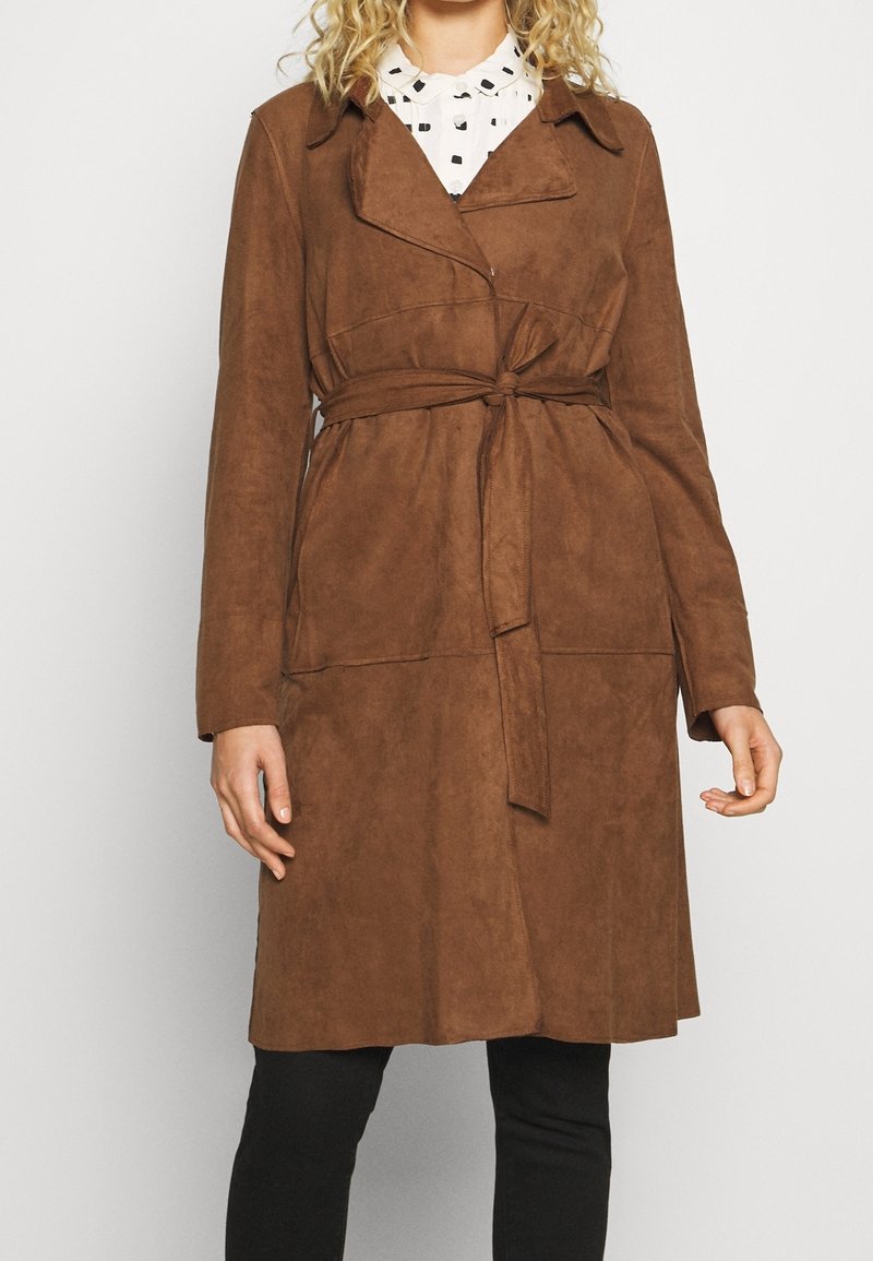 Trench-coat marron en suédine avec une taille nouée, un col à revers et des manches longues. Comprend une poche avant unique et une coupe décontractée.