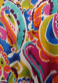 Tissu lumineux avec des motifs paisley abstraits et colorés en orange, rose, bleu, vert et jaune sur fond blanc.