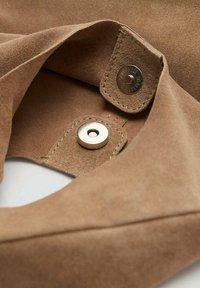 Hnedá semišová tkanina s prešívanými okrajmi, so strieborným cvokom a detailom v podobe kruhovej kovovej nity.