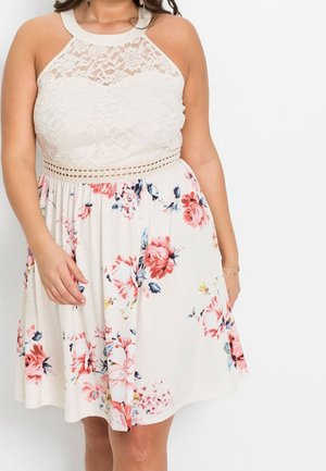 Bloemrijk jurk met een kanten lijfje, halternek en geplooide rok. Bevat roze en blauwe bloemen op een crèmekleurige achtergrond. Korter dan de knie.