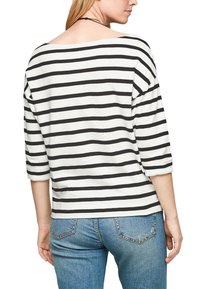 Černobílé pruhované tričko s tříčtvrtečními rukávy a širokým výstřihem; měkká látka; v kombinaci s modrými džíny.