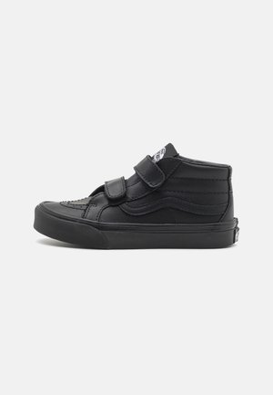 Czarny sneaker typu mid-top z dwoma paskami na rzep, teksturowaną gumową podeszwą i przeszyciami po bokach na jednolitym tle.