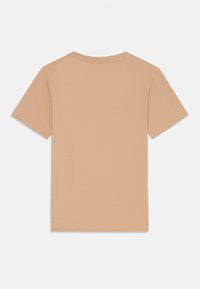 T-shirt à manches courtes et col rond en tissu beige clair. Texture lisse avec un design simple et sans ornements au dos et des détails de couture soignés.