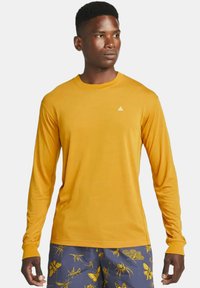 Long-sleeve shirt in bright yellow with a round neckline and a small white logo on the chest; smooth fabric, regular fit.